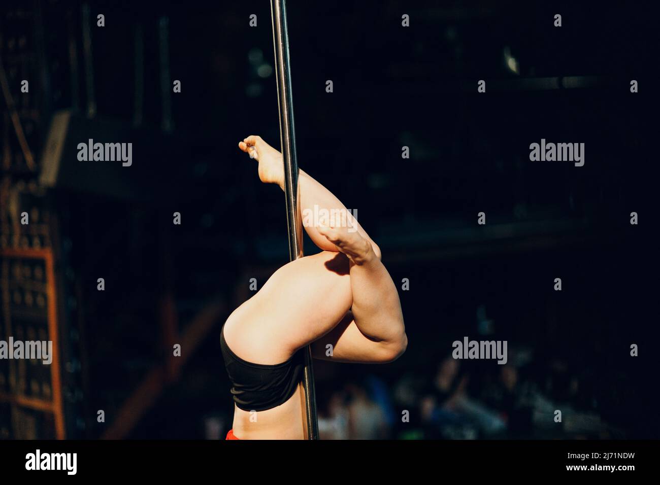 Woman striptease dancer dancing pole dance on scene. Stock Photo
