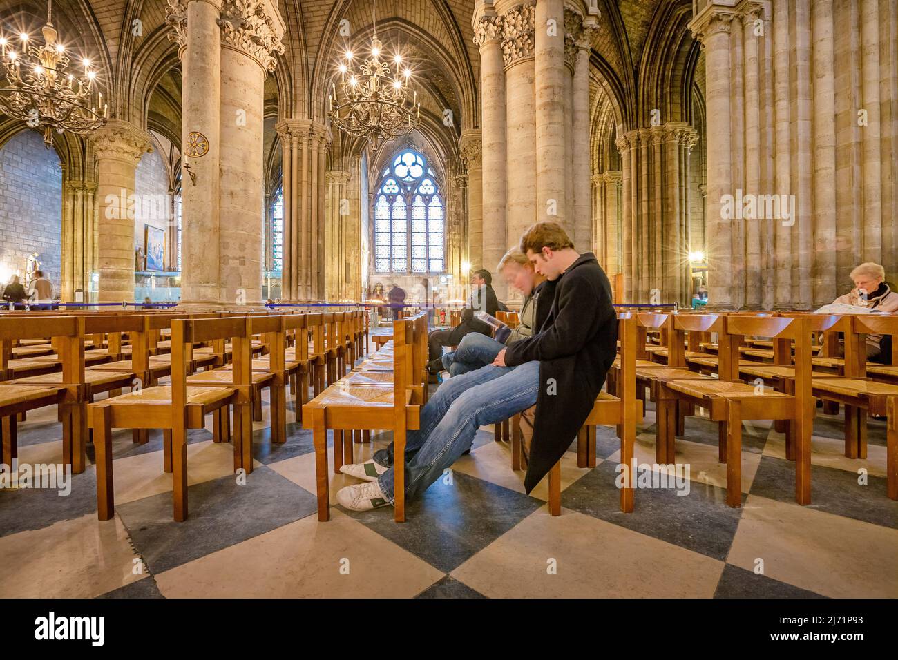 People sit inside the Notre Dame Cathedral in Paris France Stock Photo