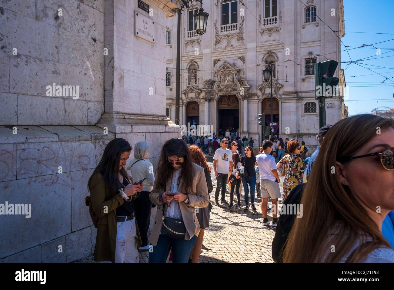 Tourists look at phones outside a church in Lisbon, Portugal Stock Photo
