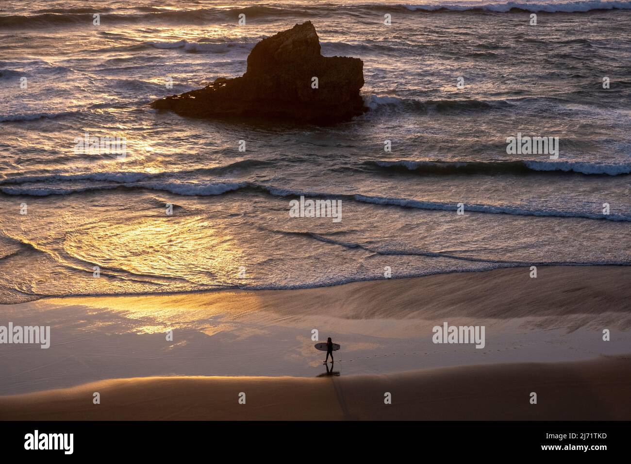 Surfer with surfboard walks along Praia do Tonel, Sagres, Portugal Stock Photo