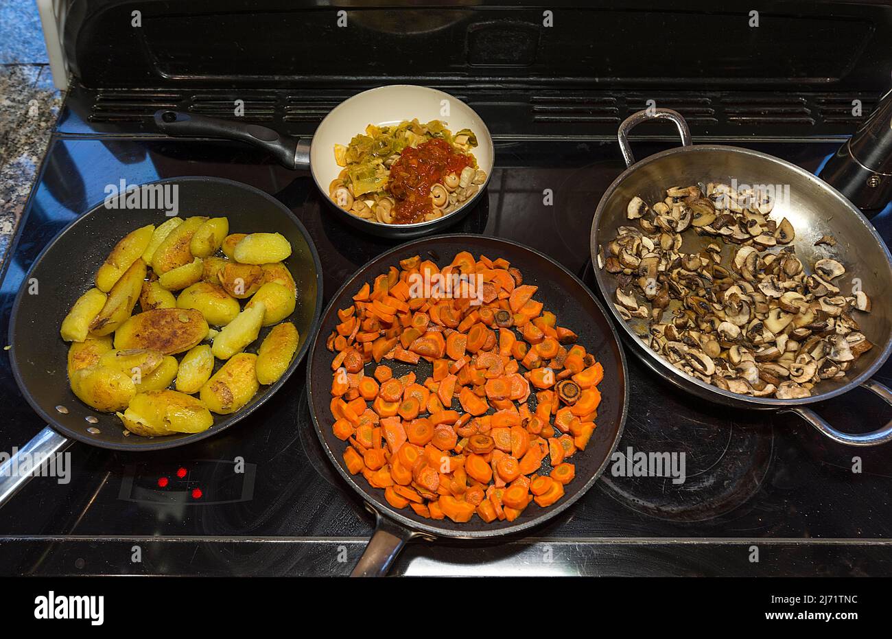 Pfannen mit Gemuese und Bratkartoffeln auf dem Herd, Bayern, Deutschland Stock Photo