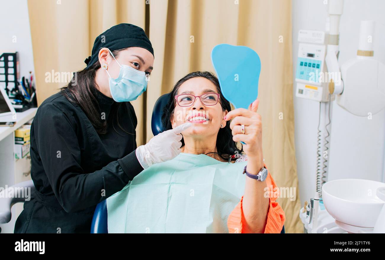 Satisfied female client in dental clinic looking at mirror, Dentist
