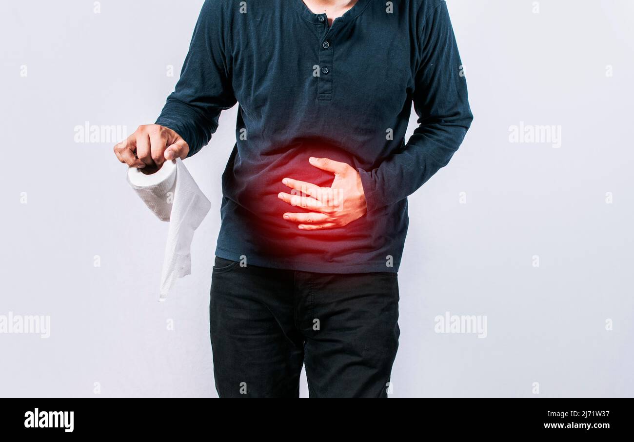 Person with toilet paper with stomach problems on isolated background, Concept of a person with digestive and diarrhea problems, Man with stomach Stock Photo