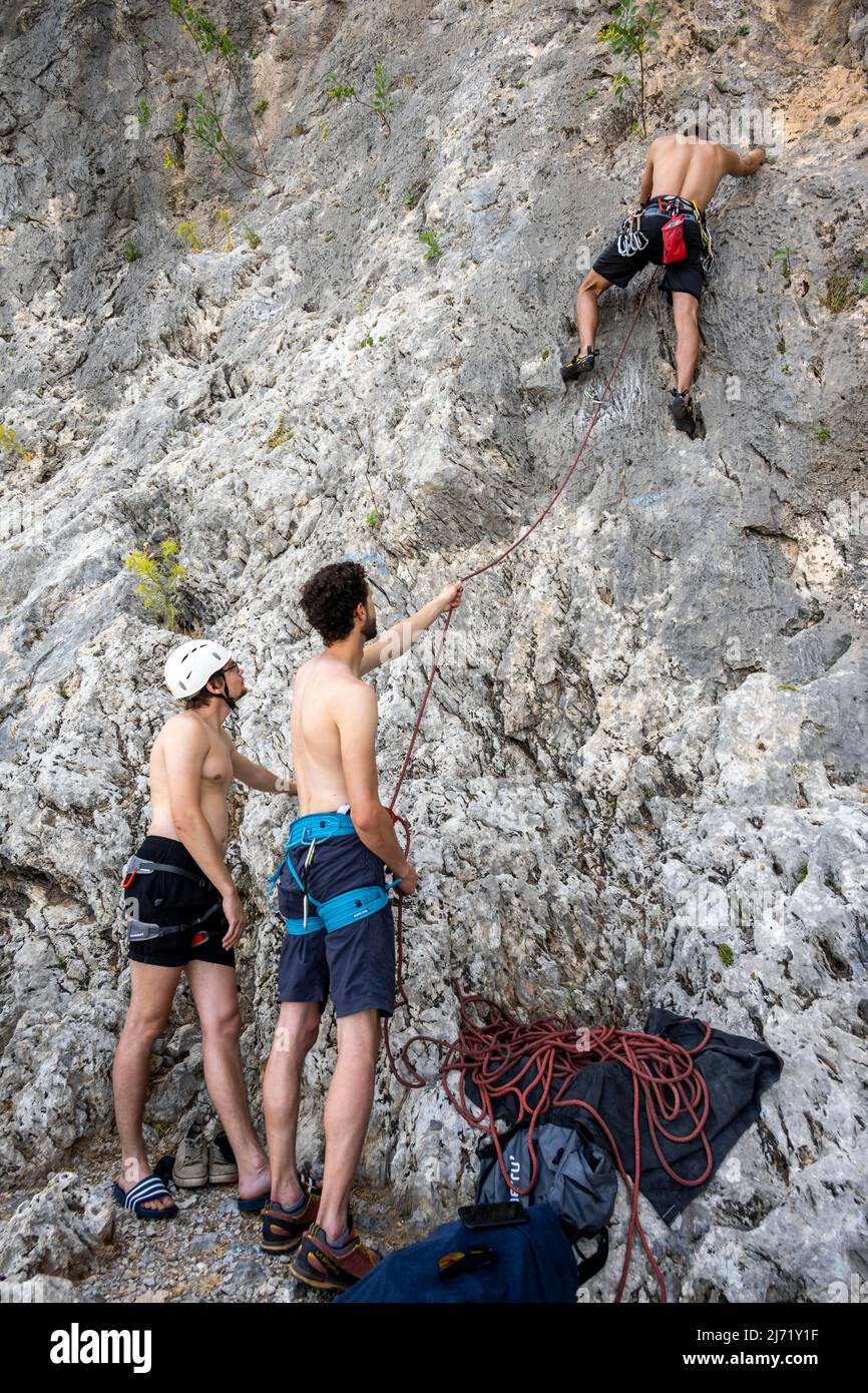 Young man belays a climber on lead, sport climbing, Kalymnos, Dodecanese, Greece Stock Photo