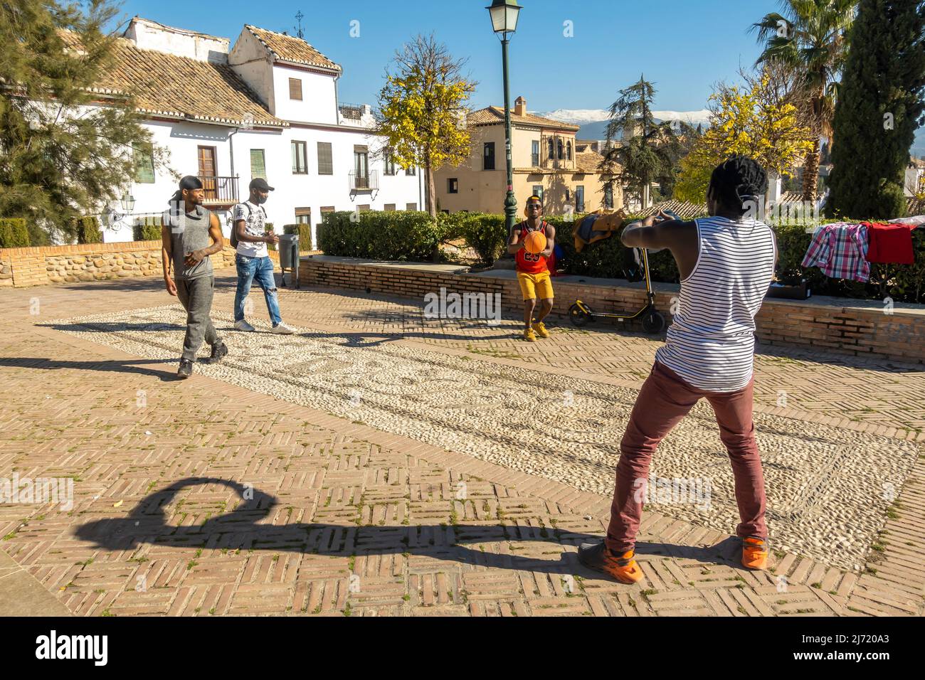 Four black young men playing basketball at spontaneous location in historic centre of Granada on C San Ncolas, Andalucia, Spain Stock Photo