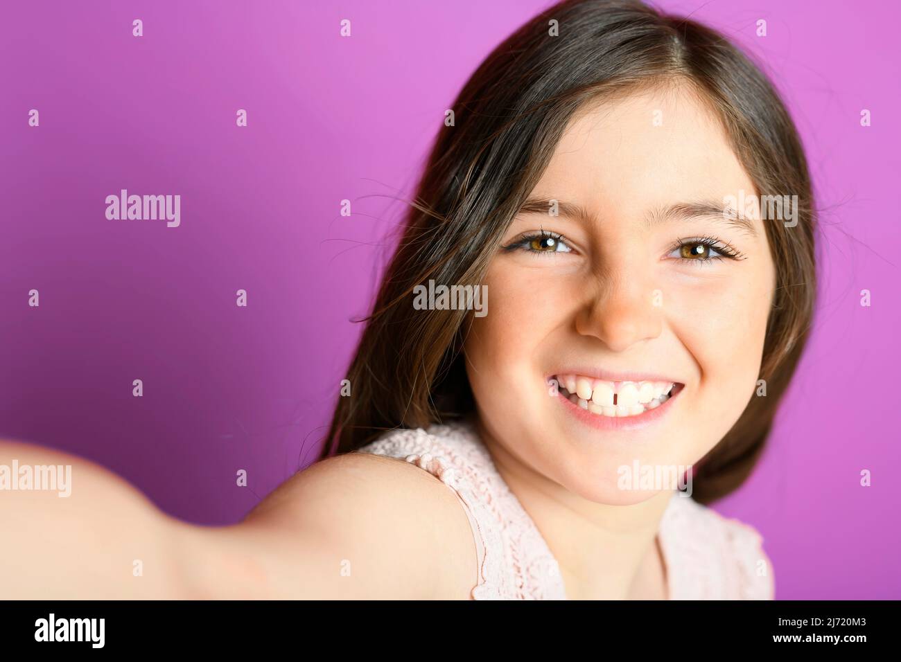 cute child with dungarees over purple background on studio doing selfie Stock Photo