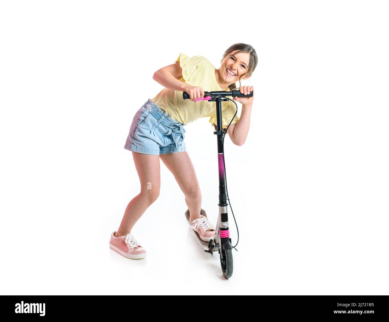 Happy little girl riding her scooter isolated on white. Stock Photo