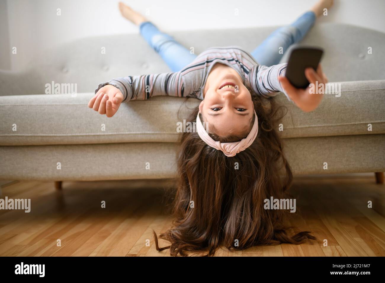 Girl Changing Channel With Remote Control In Front Of Television At Home upside down Stock Photo