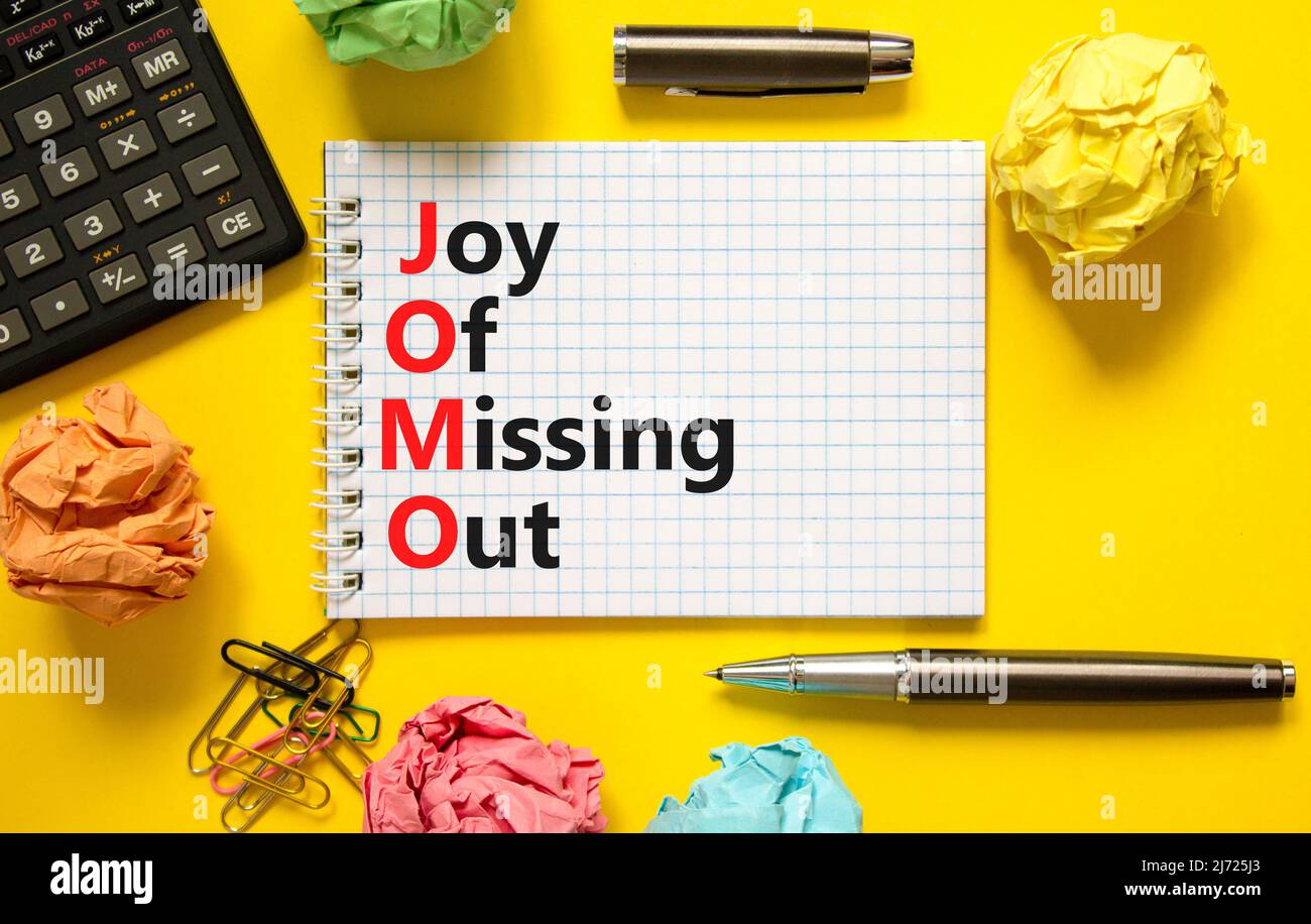 JOMO joy of missing out symbol. Concept words JOMO joy of missing out on white note on a beautiful yellow background. Black calculator. Business JOMO Stock Photo