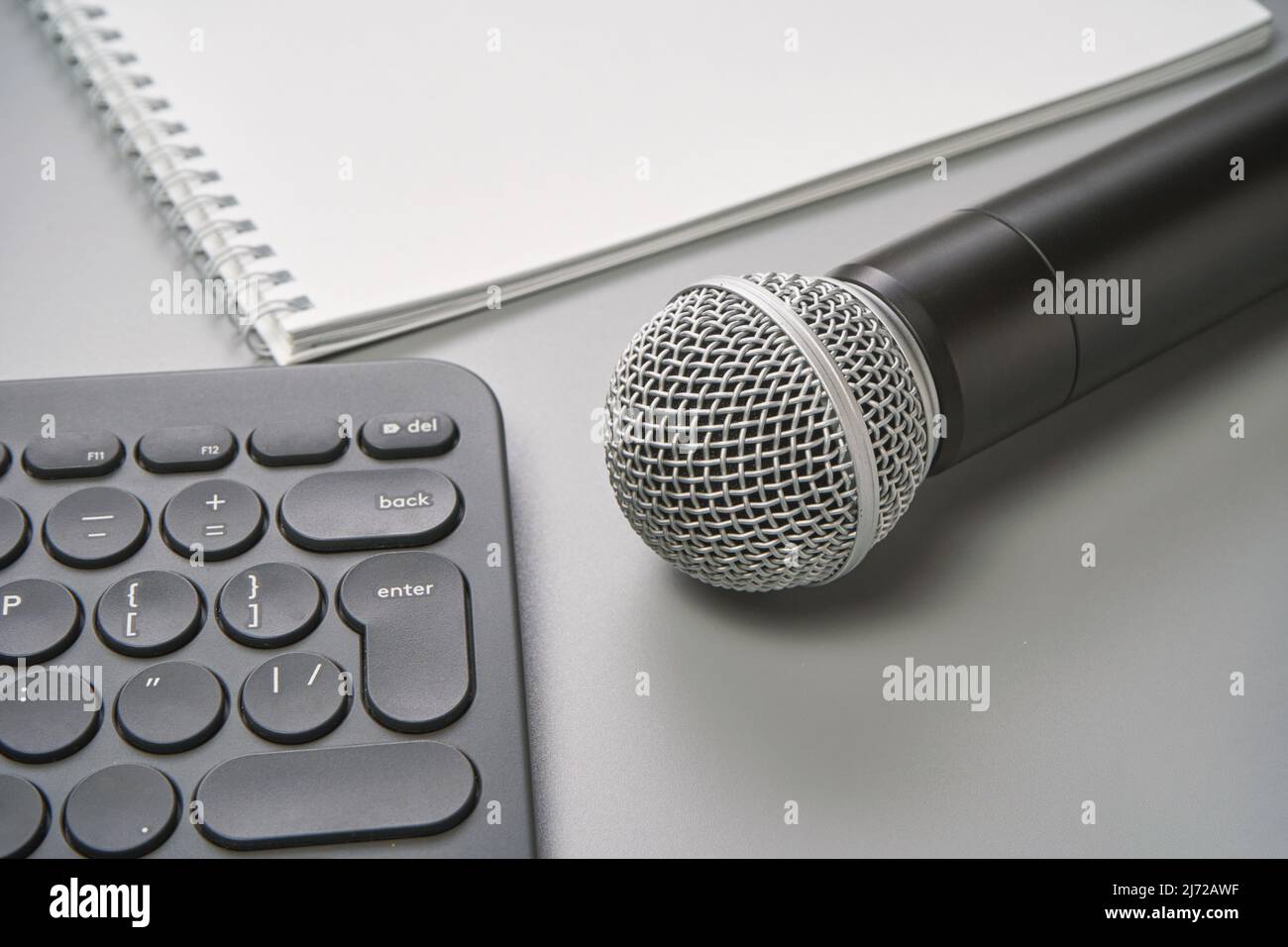 Podcast concept. White notebook with blank sheet. Black microphone, notebook and keyboard. Audiobook and podcasting. Audio technology. Home school teaching Stock Photo