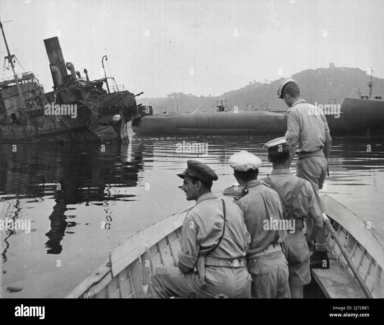 A huge Japanese cargo carrying submarine being of observed by Australian Naval personnel. This submarine was found in the Yokosuka Naval Base when it was occupied by the British Landing Force. Badly damaged ship in background. September 24, 1945. (Photo by Australian Official Photo). Stock Photo