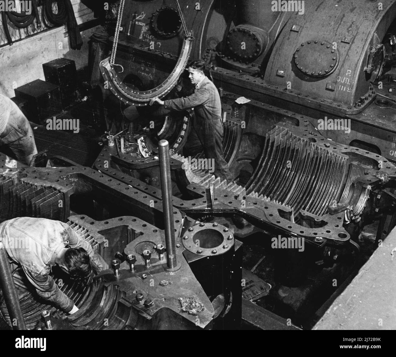 Steam Turbine Engines (d) Assembling the fixed blades of a turbine cylinder or case. The rota revolves in this, each wheel of rota blades fitting in between the wheels of the fixed blades in the cylinder. The rota blades are set at an angle causing the steam come through at an angle. The fixed blades of the turbine case direct the steam back to the next blades of the revolving rota. September 21, 1951. Stock Photo