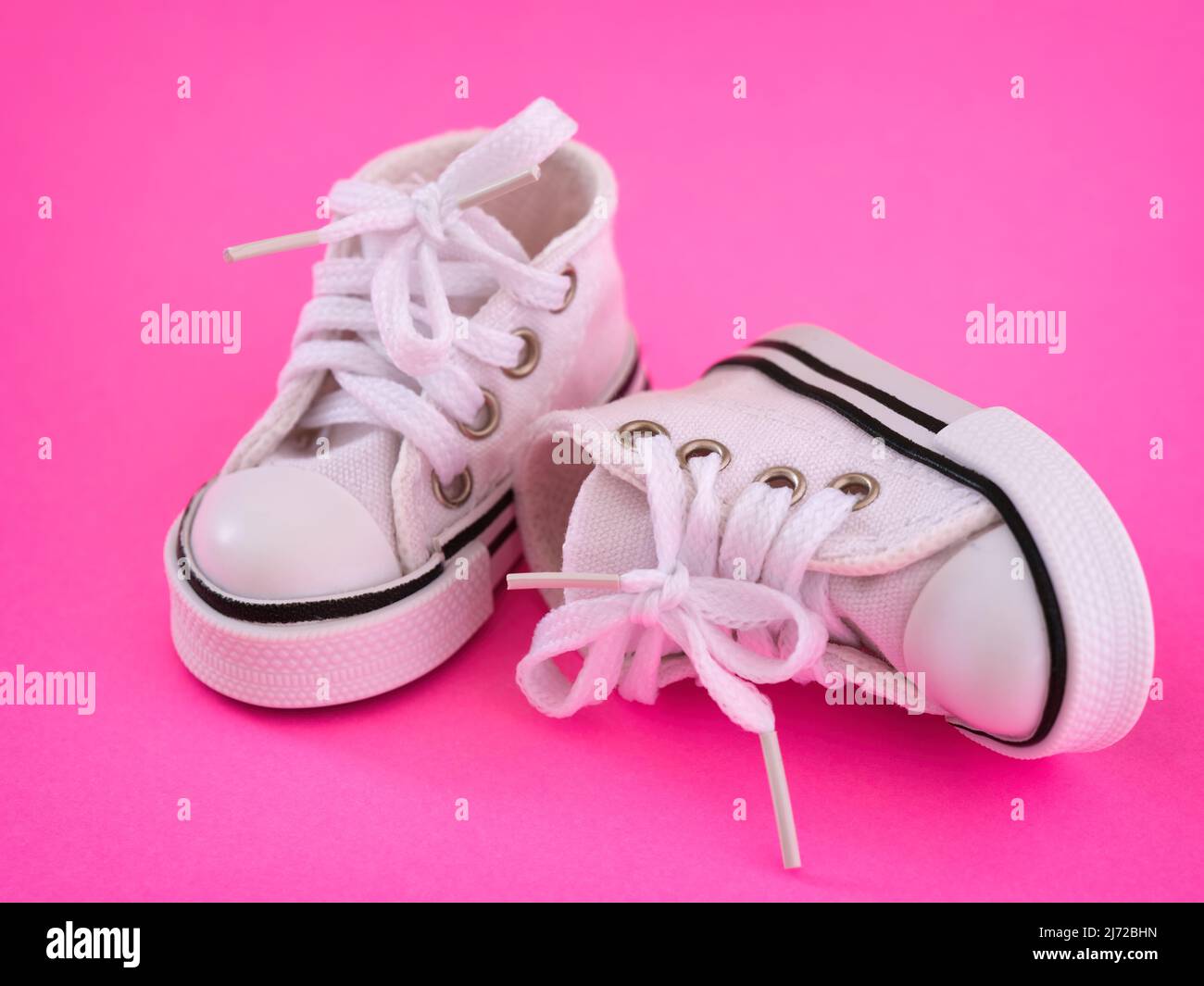 Pair of a white doll shoes on a pink background. Close-up Stock Photo