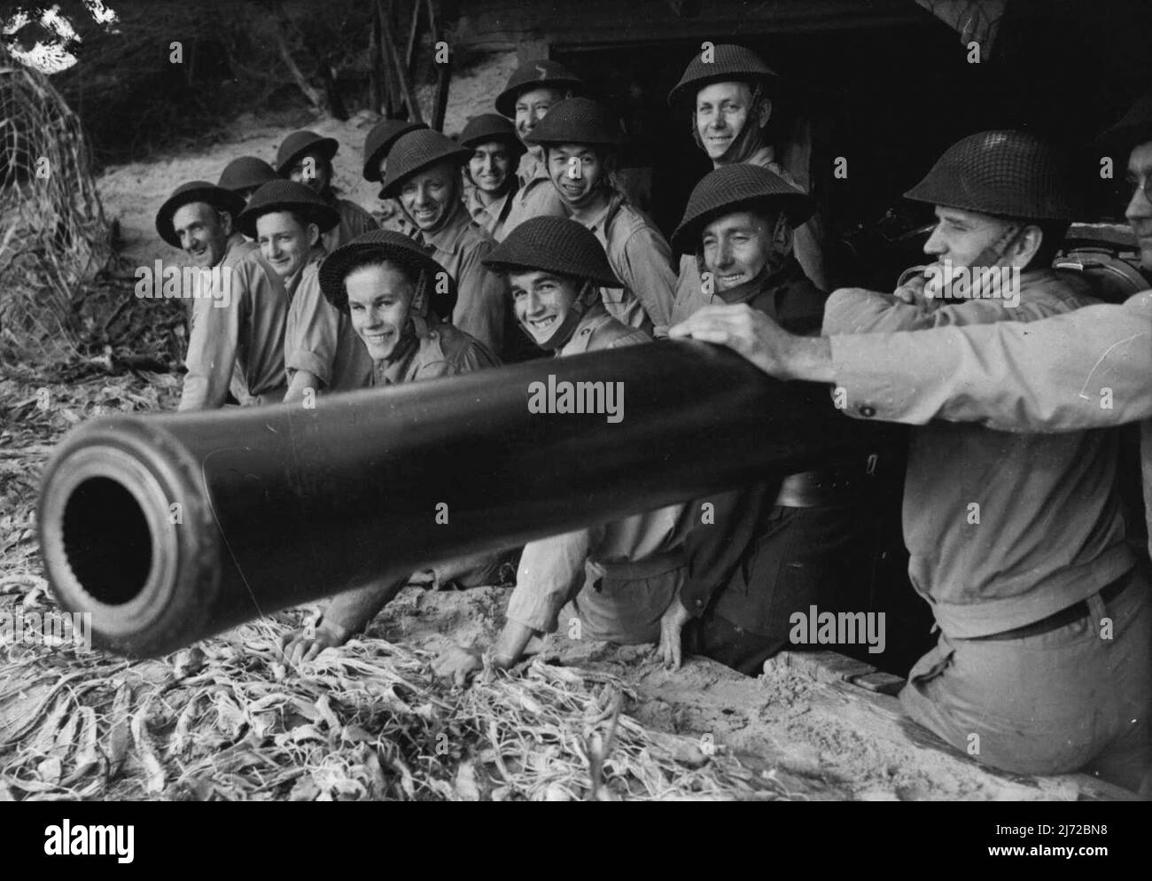 V.D.C. In Aust. Group of V.D.C. who man (part time) coastal gun off duty rest beside their gun. October 11, 1943. (Photo by H. Rodda). Stock Photo