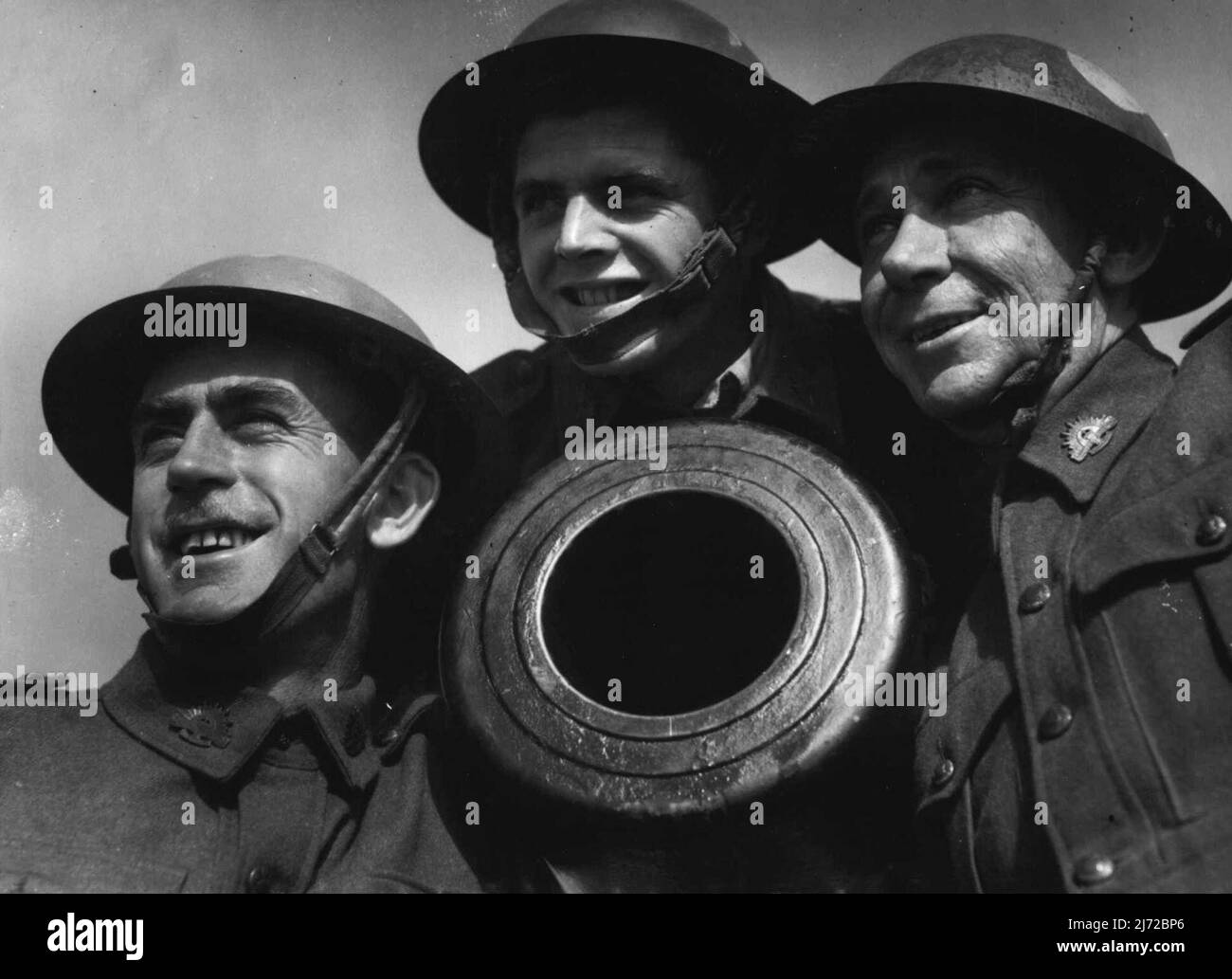 Members of the VDC grouped around the end of a coastal gun, (left to right) Privates M. McIntyre, W. Liddle and R. Walker. They are at present undergoing training in the use of coastal defense guns. May 31, 1943. Stock Photo