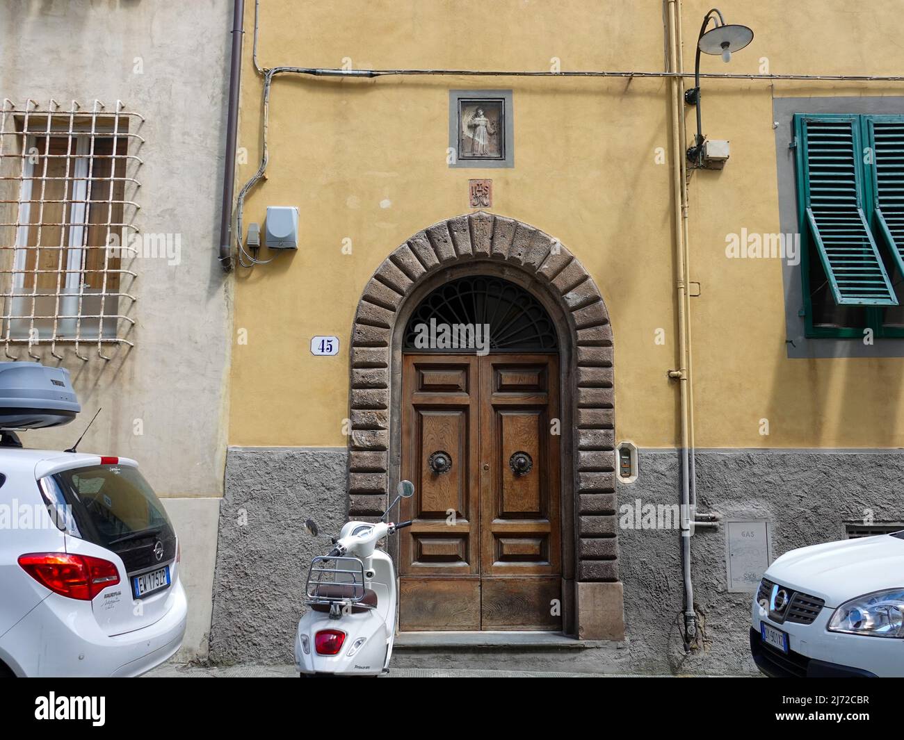 Religious, Christian symbols over doorway entrance to residential building  in Lucca, Italy. Stock Photo