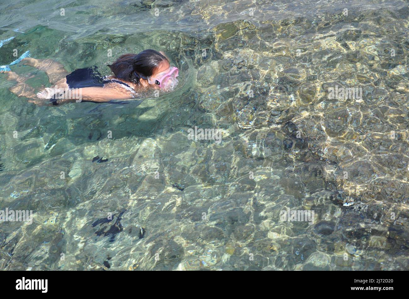 Mali Losinj,Croatia July 2020. Girl diving into beautiful clear Adriatic Sea.Happy family,girl in snorkeling mask dive underwater with tropical fishes Stock Photo