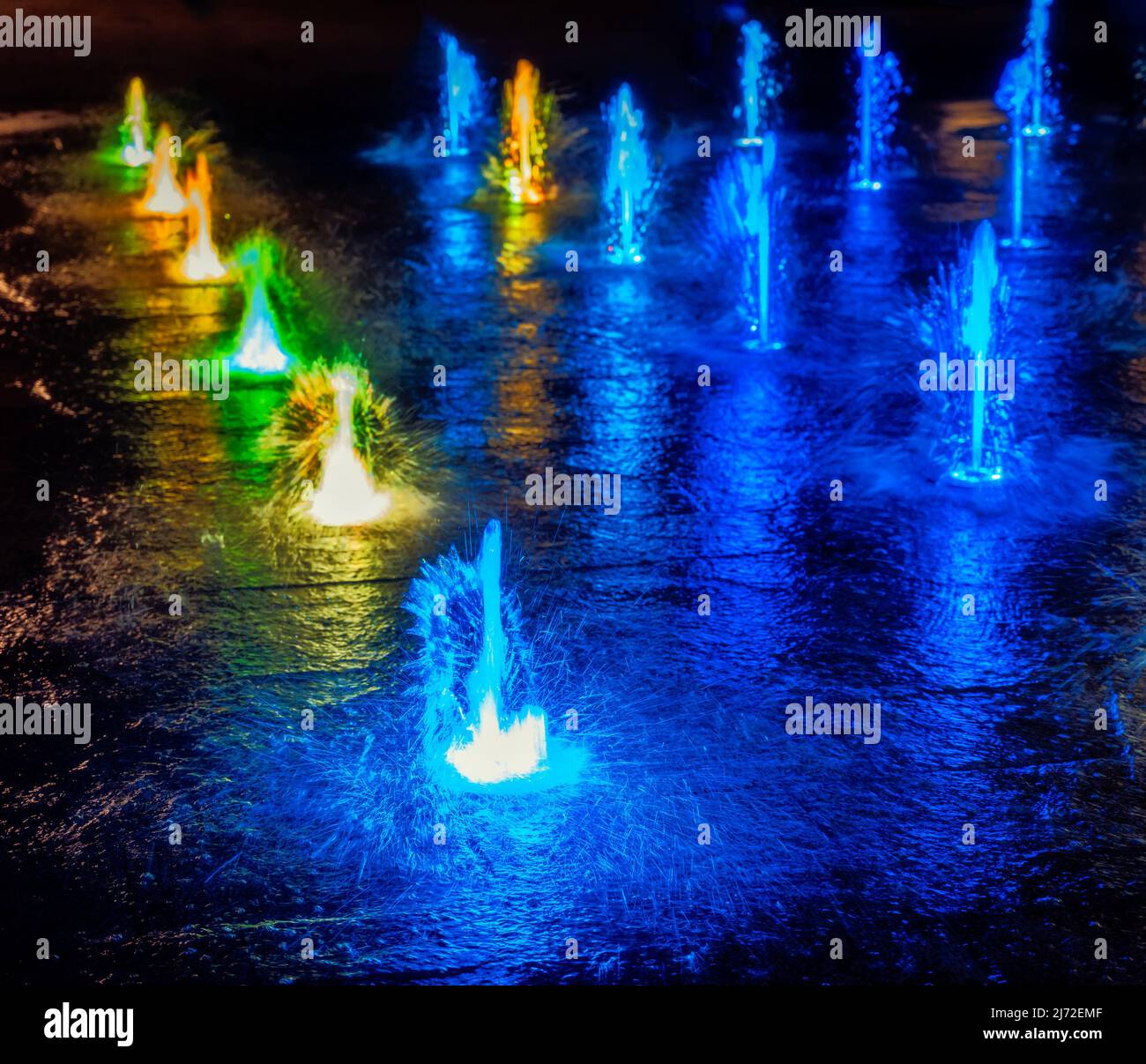 Colourful illuminated waterspout fountain at night Stock Photo