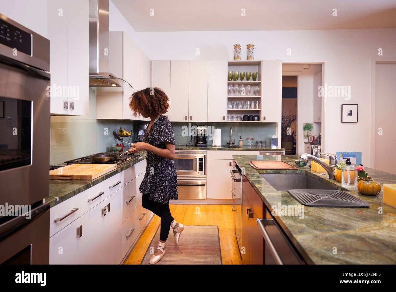 Female ballet dancer cooking in a residential kitchen Stock Photo