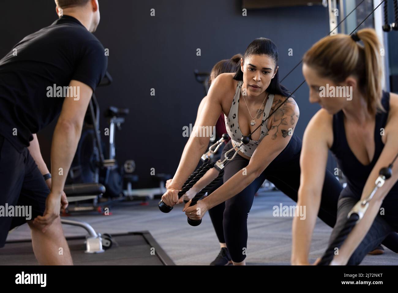 Three women working out on cable pulley machine during fitness class