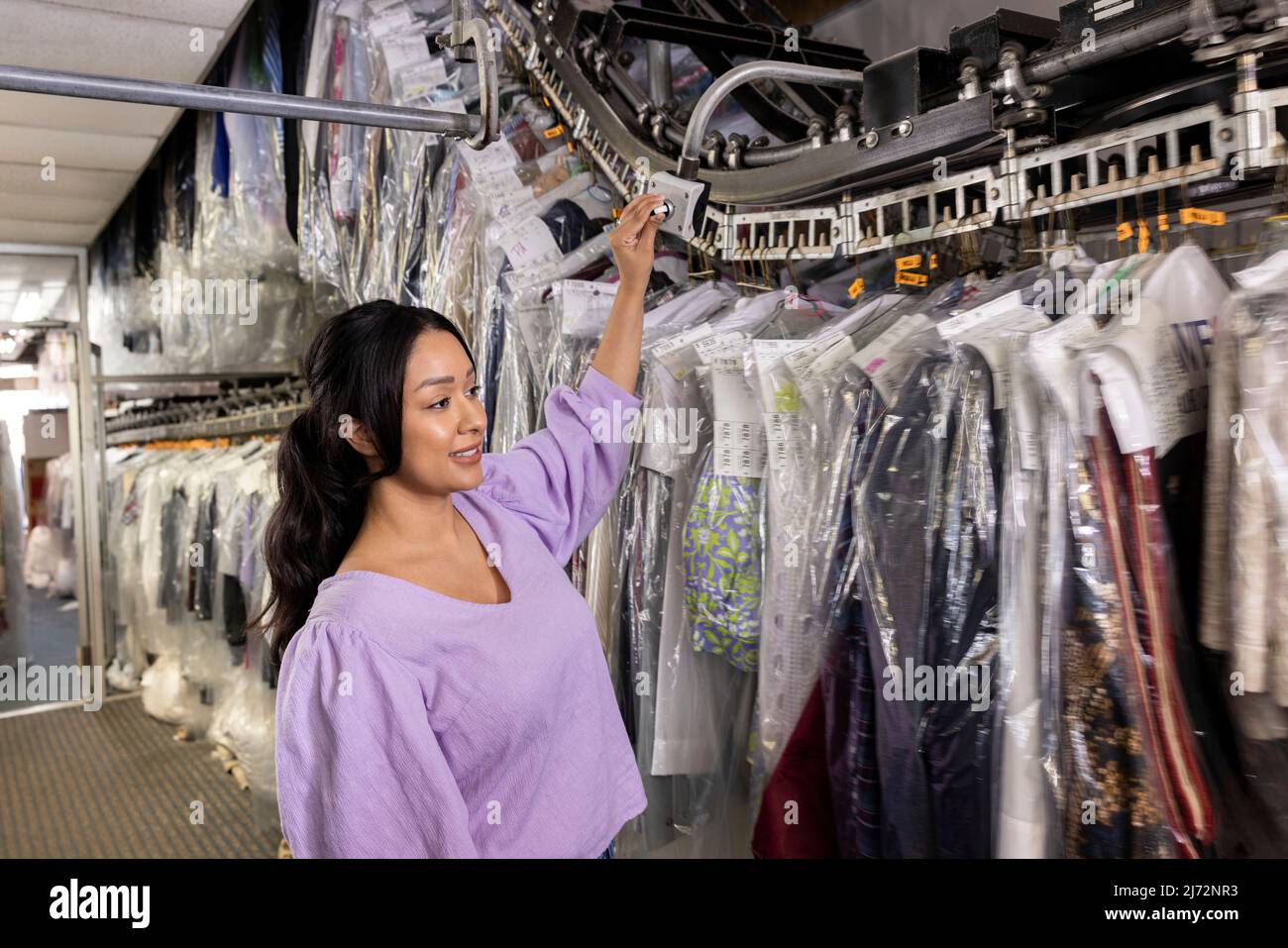 Woman dry cleaner checking clothes on rack Stock Photo Alamy