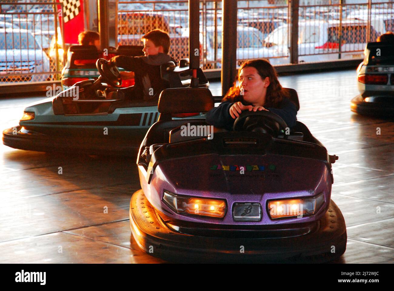 A young girl enjoys a turn on the bumper cars at an amusement park Stock Photo