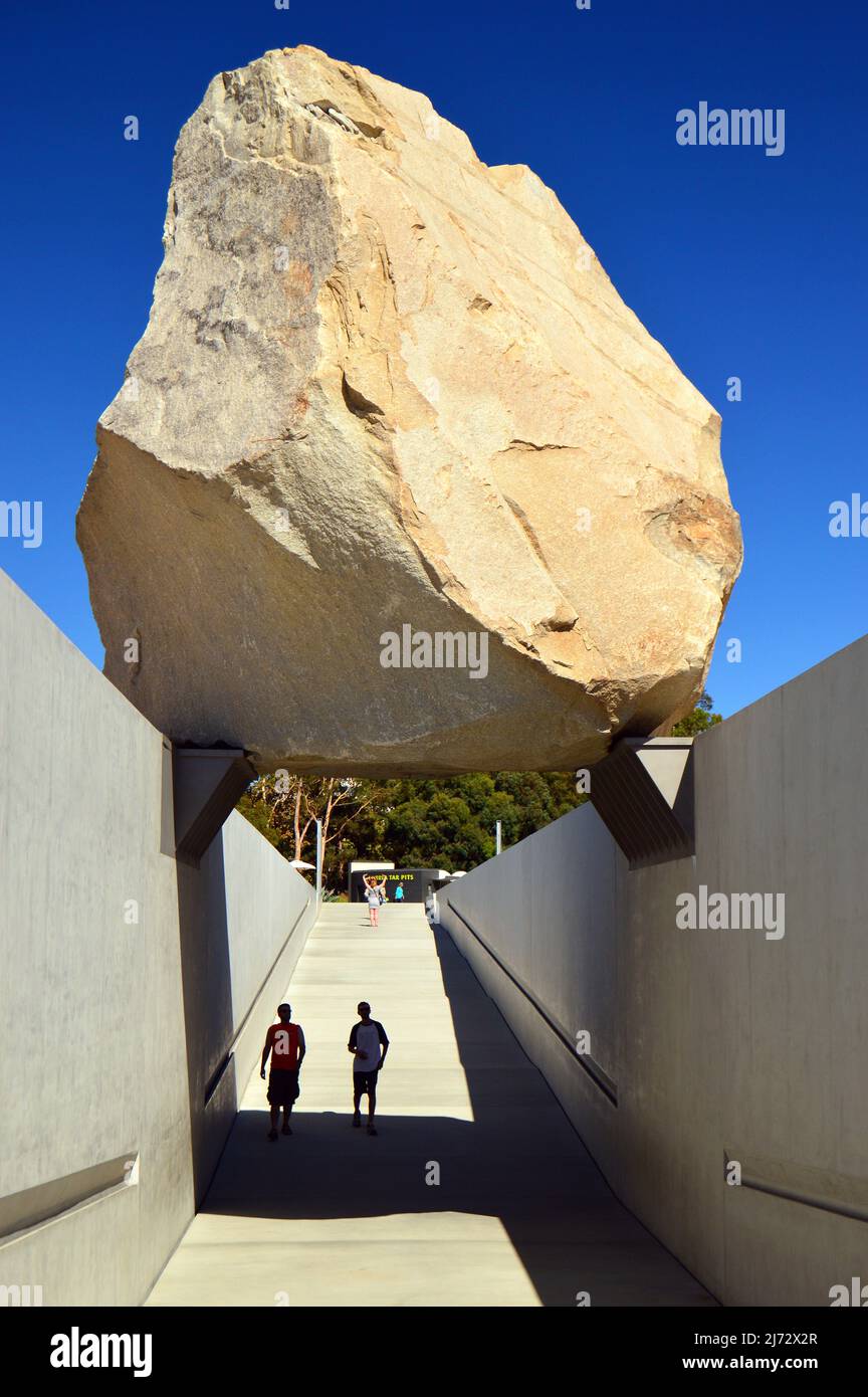 Two young men stand under Levitated Mass, a sculpture by Michael Heizer, at the Los Angeles County Museum of Art Stock Photo