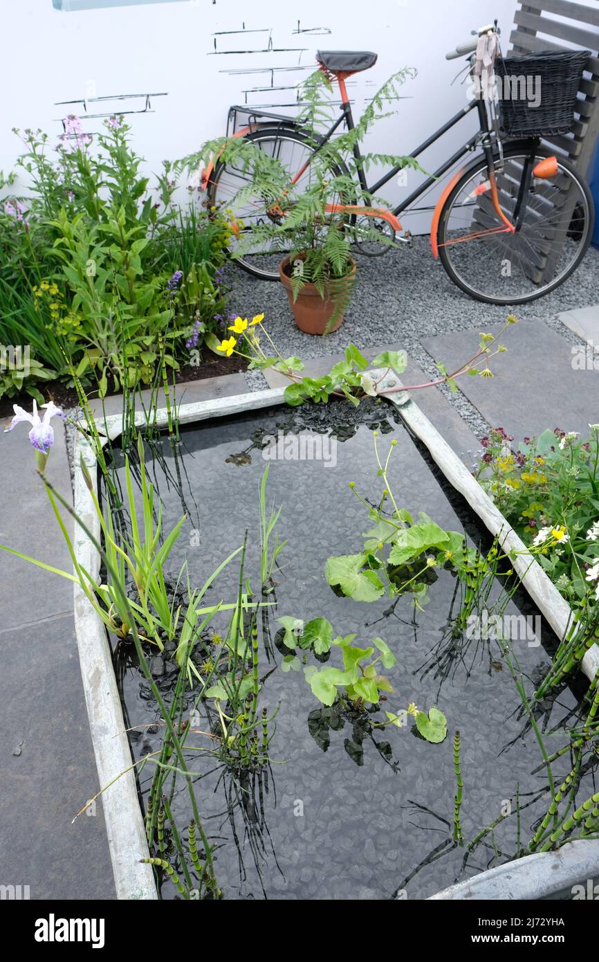 Malvern, Worcestershire, UK – Thursday 5th May 2022 – The RHS Affordable Garden features designs with a budget of under £1,000 - this is the Side Garden featuring an old galvenised tank turned into a water plant container. Photo Steven May / Alamy Live News Stock Photo