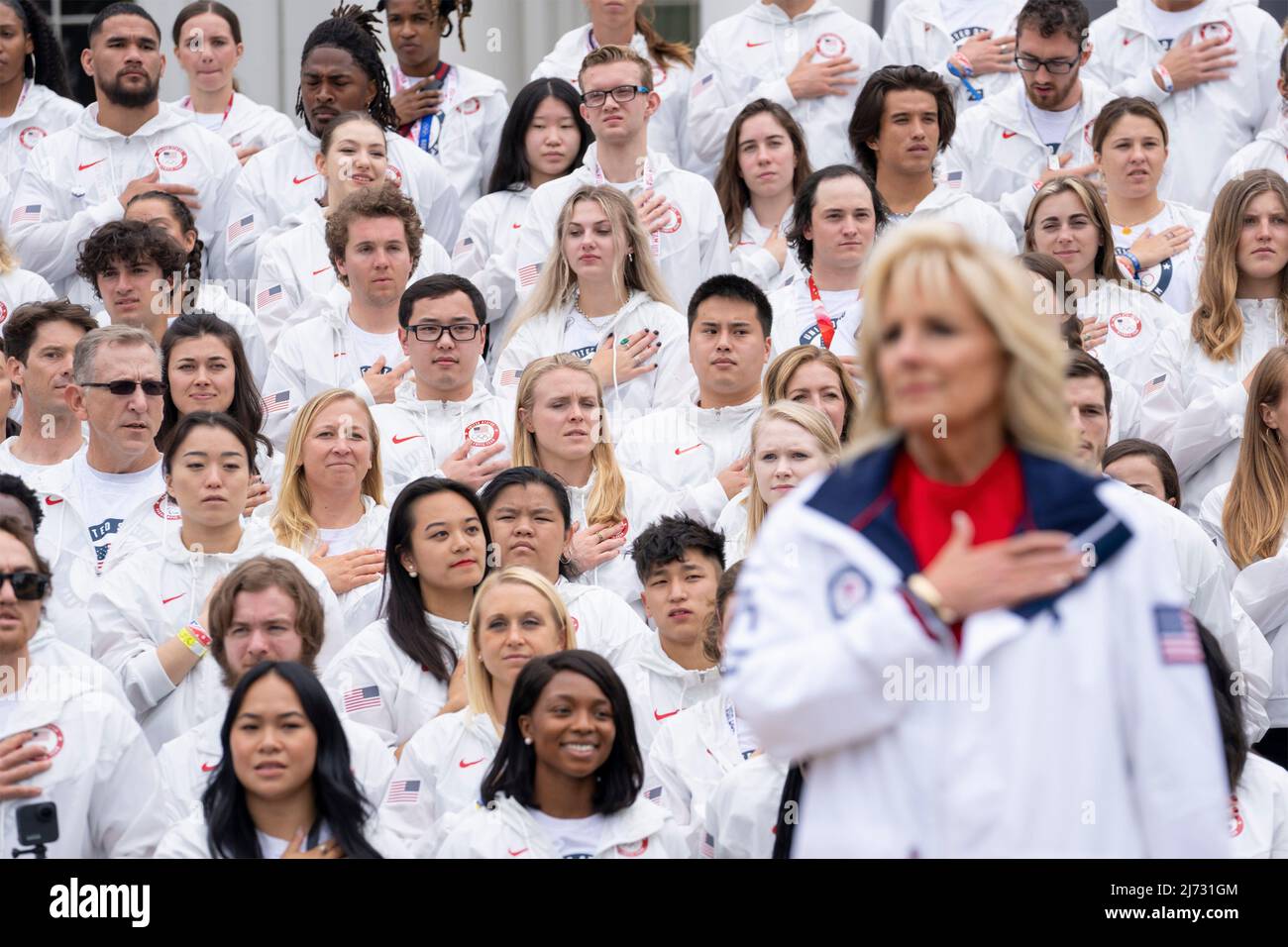 Washington, United States of America. 04 May, 2022. U.S. Olympic team athletes stand for the national anthem alongside First Lady Jill Biden during an event welcoming the athletes that participated in the Tokyo 2020 Summer Olympic and Paralympics, Beijing 2022 Winter Olympic and Paralympics, on the South Lawn of the White House, May 4, 2022 in Washington, D.C.  Credit: Cameron Smith/White House Photo/Alamy Live News Stock Photo