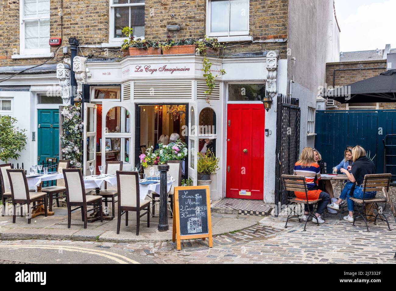 Outside diners enjoying delicious food at  La Cage Imaginaire Restaurant, a French bistro in the quaint cobbled street of Flask Walk Hampstead NW3 Stock Photo