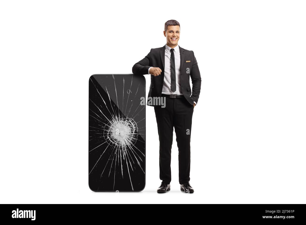 Man in a black suit and tie leaning on a big smartphone with a broken screen isolated on white background Stock Photo