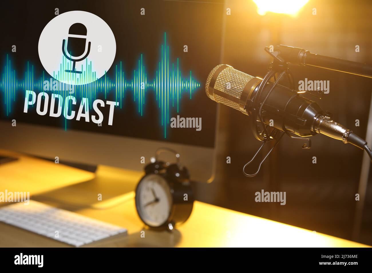 Stand with professional microphone near workplace with computer in dark room Stock Photo