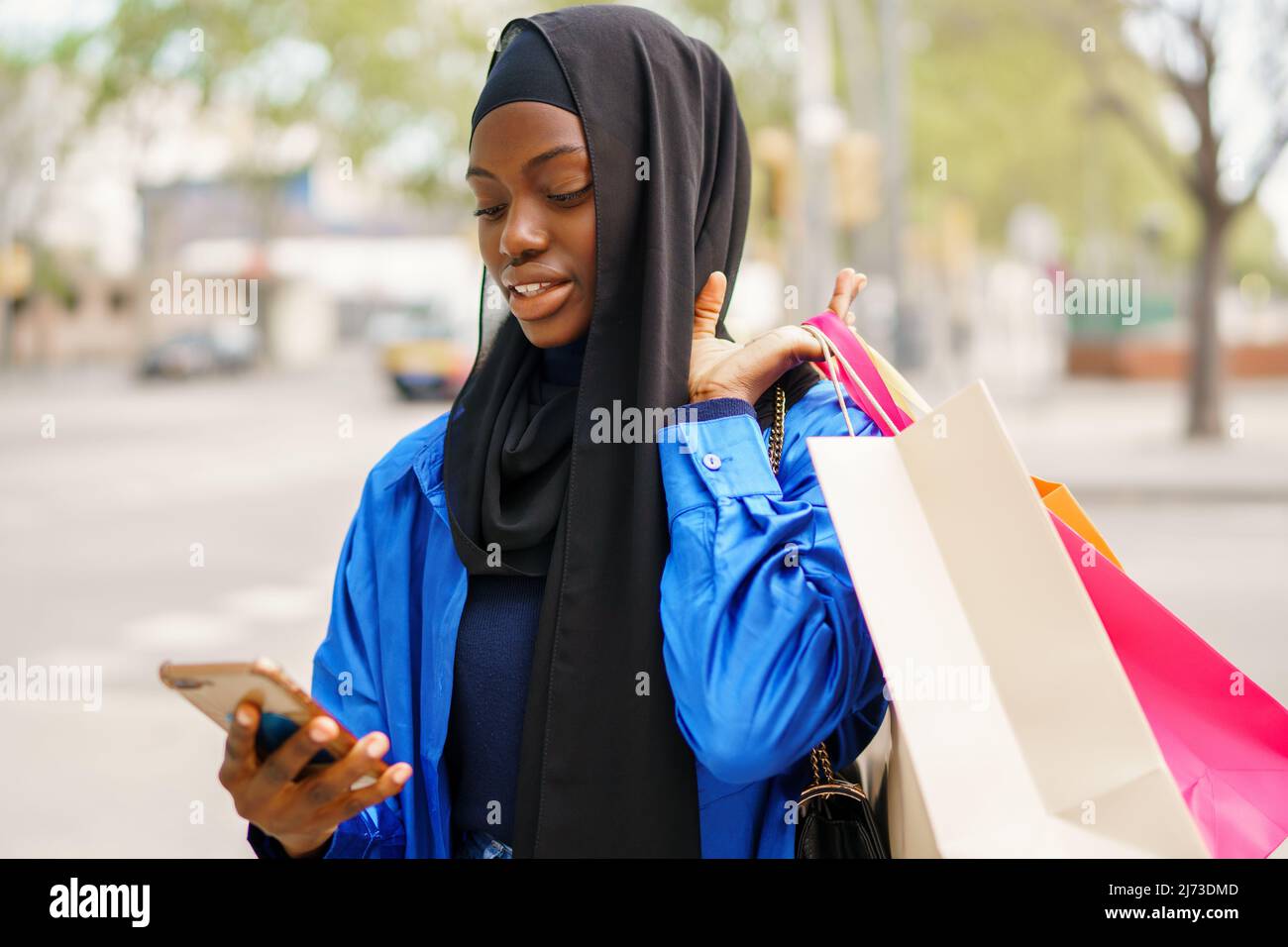 Muslim shopper texting on smartphone Stock Photo
