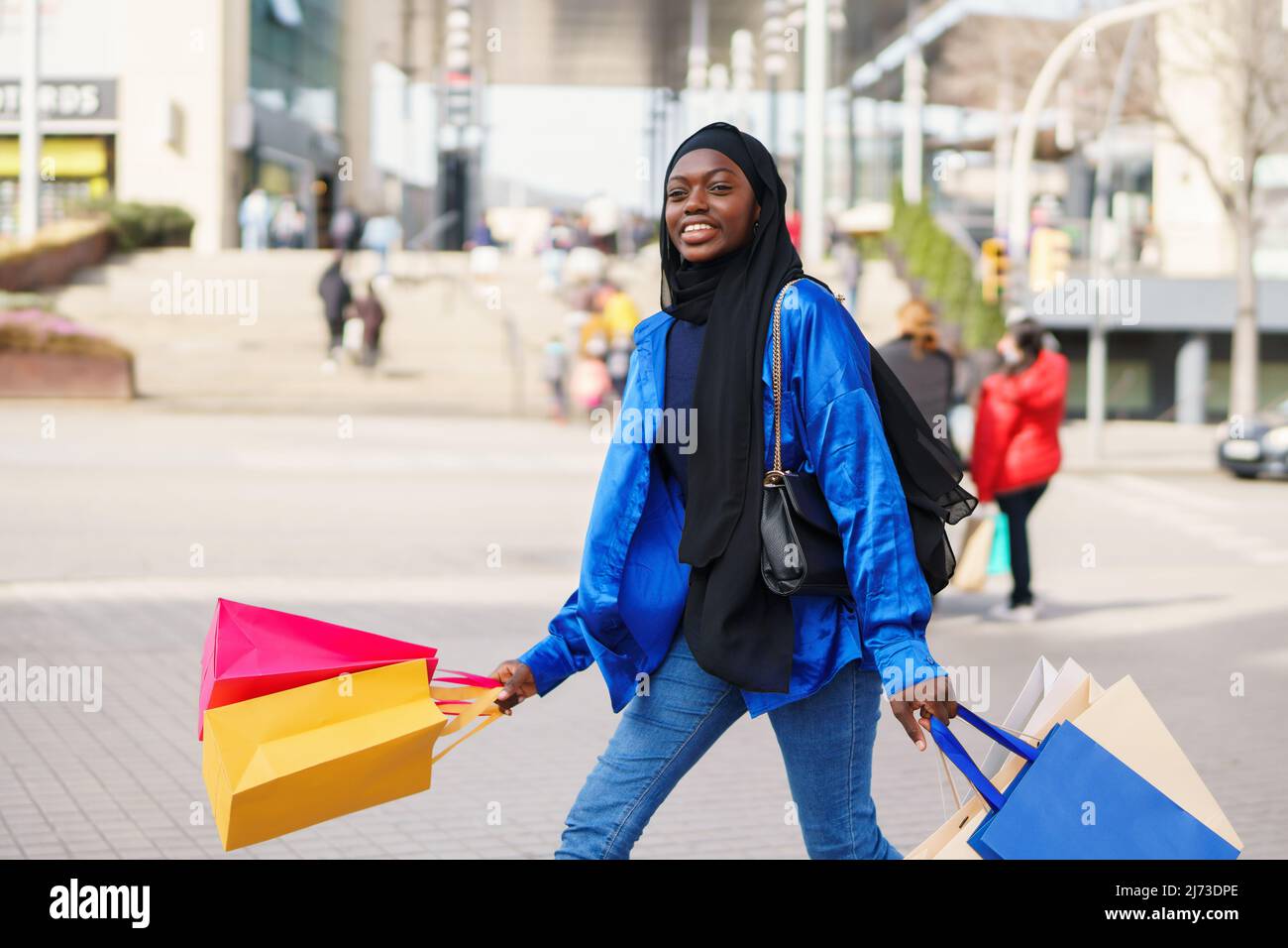 Glad Muslim shopper walking in modern city Stock Photo