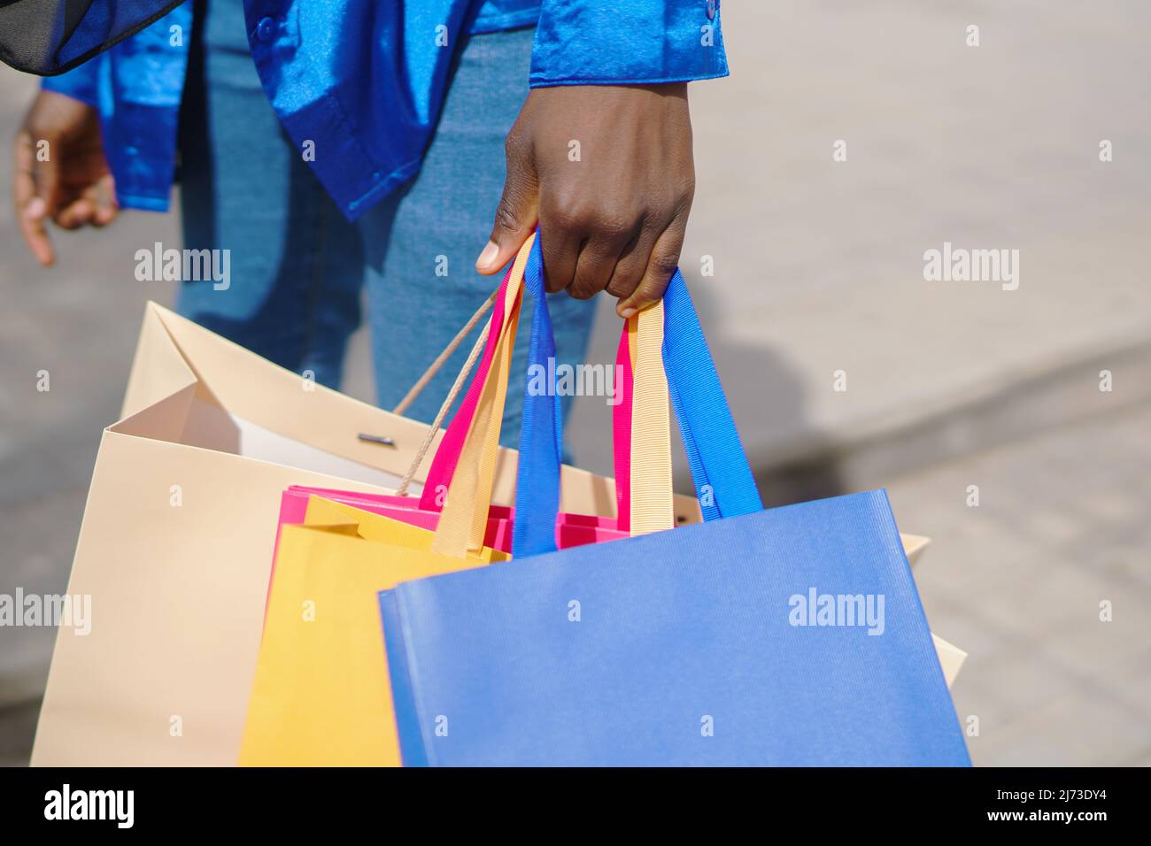 Crop black woman with shopping bags on street Stock Photo
