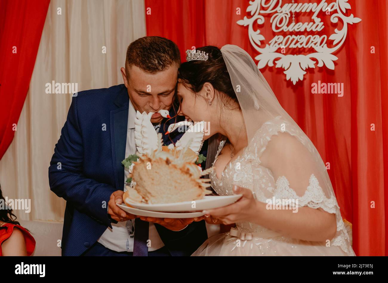groom and bride in veil take a bite of the traditional Ukrainian wedding loaf cake korovai Slavic Ukrainian Russian traditions Stock Photo