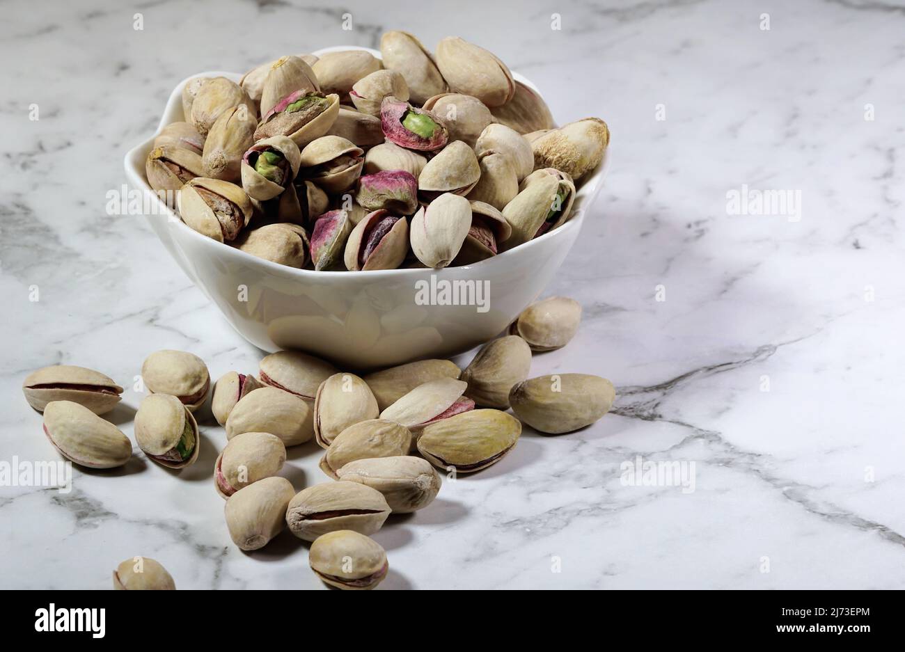 small bowl of pistachio nuts on the bench Stock Photo