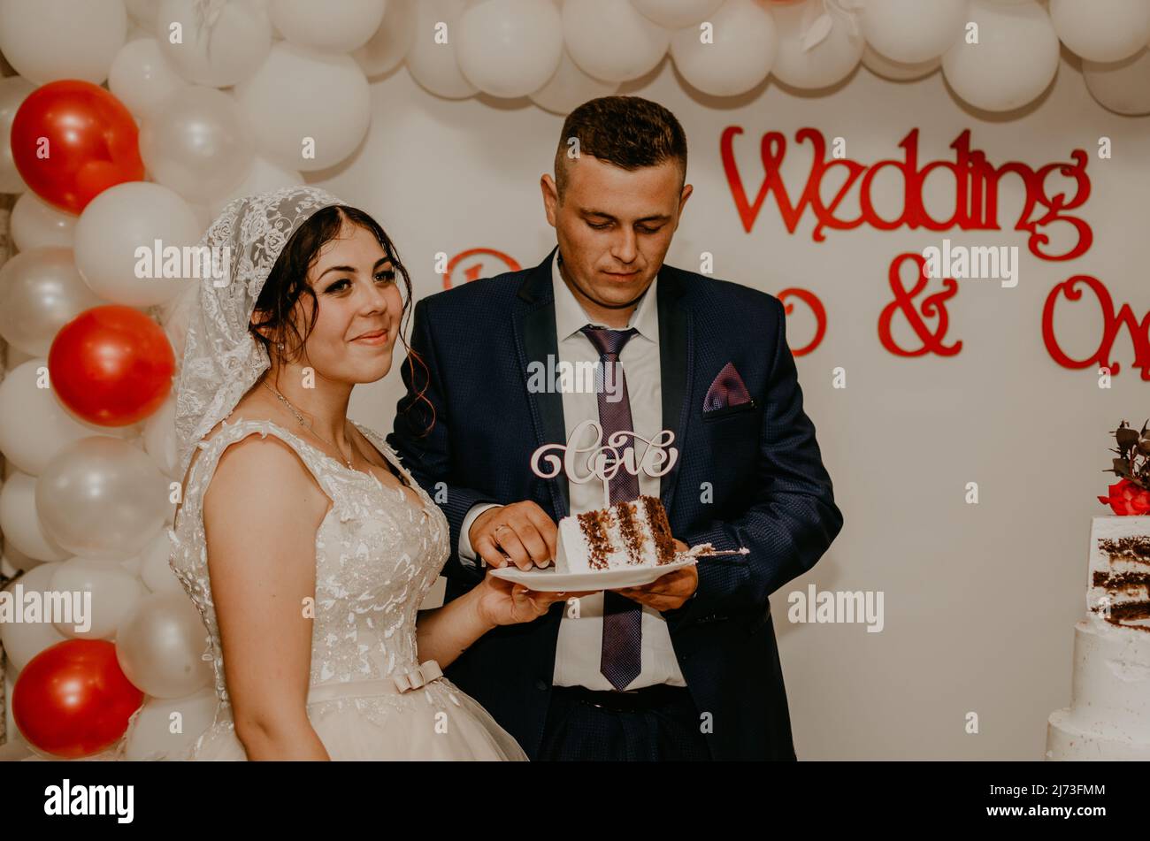 groom and bride at wedding cut their large multi-tiered white cake taste it fed from each other. Slavic Ukrainian Russian traditions Stock Photo