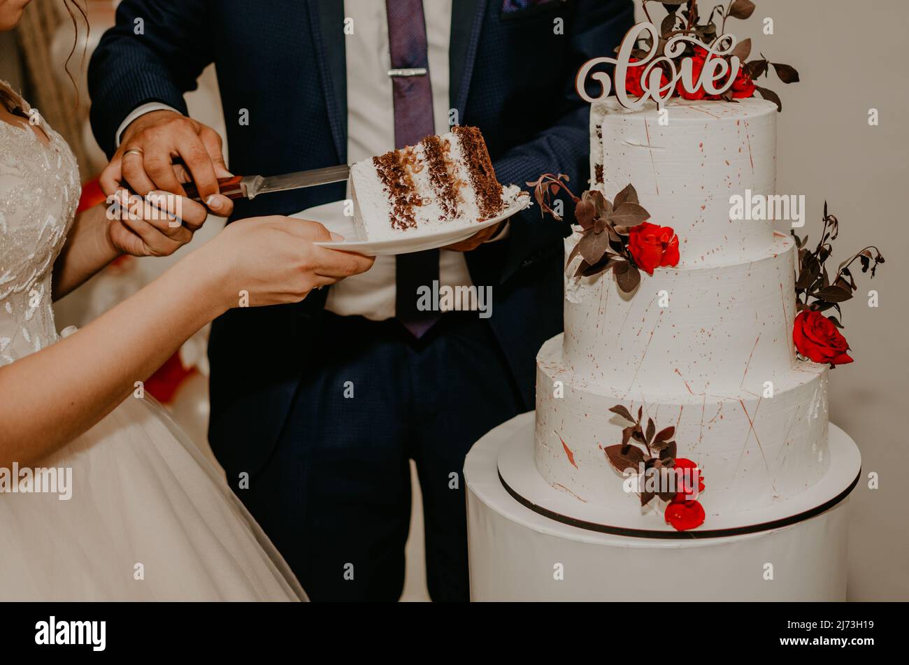 groom and bride at wedding cut their large multi-tiered white cake taste it fed from each other. Slavic Ukrainian Russian traditions Stock Photo
