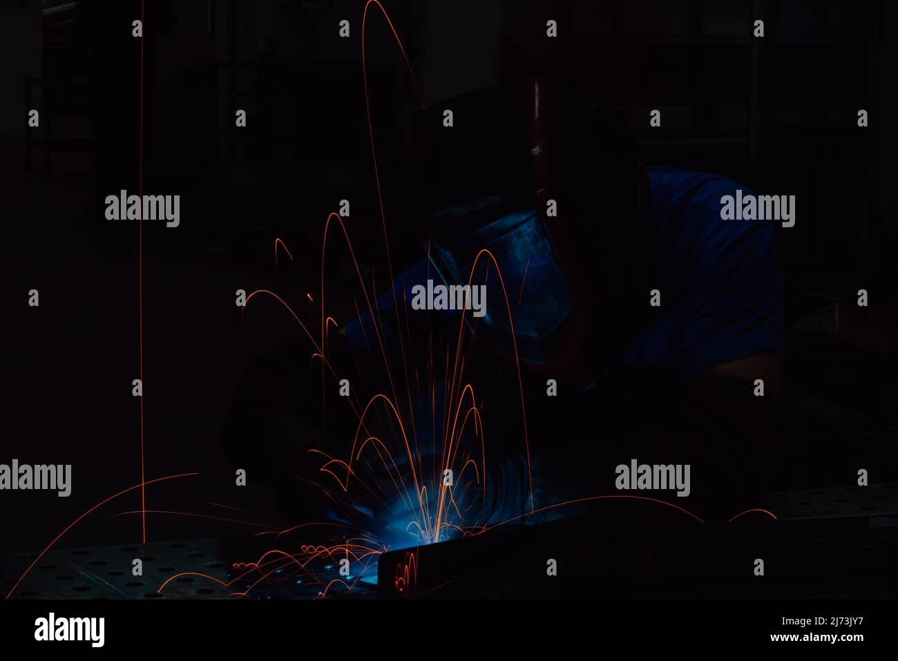 Professional Heavy Industry Welder Working Inside factory, Wears Helmet