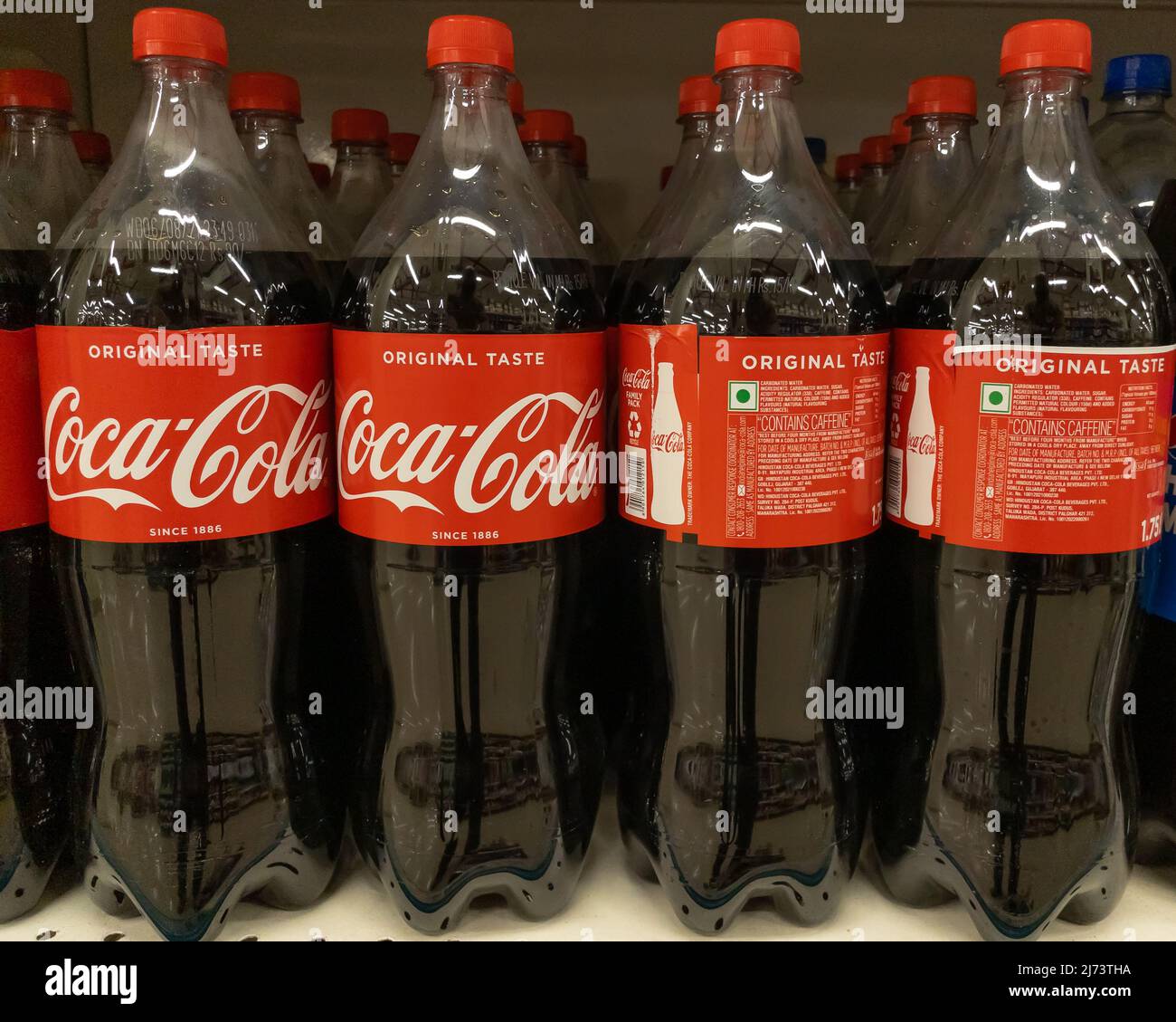 Bottles of CocaCola kept on the shelves of a supermarket for sale in