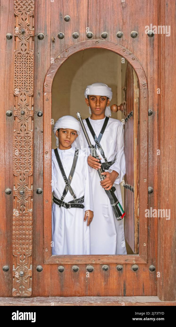 Two brothers in national dress, at the door of a restored house in the Sharjah Heritage Area, on their way to Sharjah's Heritage Days Festival. Stock Photo