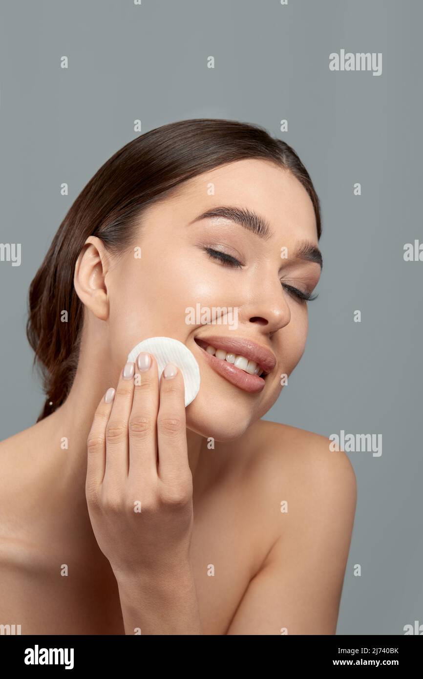 Woman Cleaning Face With White Pad. Beautiful Girl Removing Makeup White Cosmetic Cotton Pad. Happy Smiling Female Taking Off Makeup From Facial Skin Stock Photo