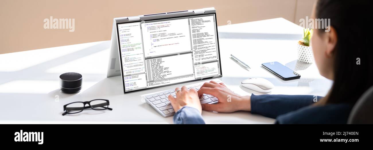 Programmer Or Coder At Office Desk Using Laptop Stock Photo