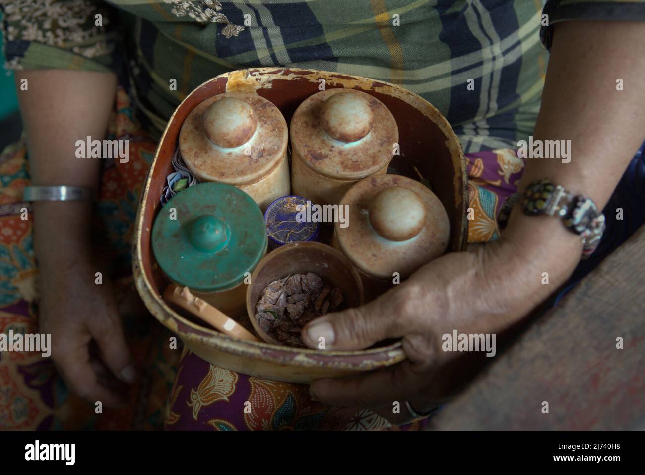 A woman showing a set of plastic vessels where she store materials for 'betel chewing' at her floating house on Musi river in Palembang, South Sumatra, Indonesia. Betel chewing—which commonly require areca nuts, slaked lime and betel leaves—is a tradition that can be found quite easily among elders in present day Malaysia and Indonesia. Areca nut, the main material for betel chewing, was a major product of Srivijaya that was mentioned by a 13th century Chinese commissioner for international trade, Chau Ju-kua (Zhao Rugua). Stock Photo