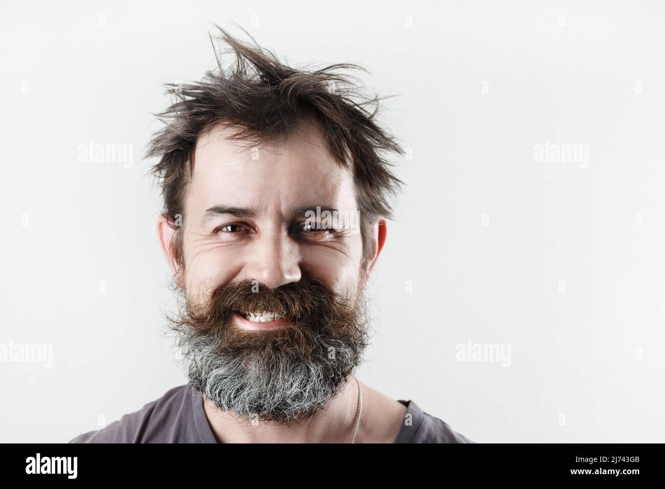 Happy smiling bearded shaggy man. Studio portrait of an unshaven man. Stock Photo