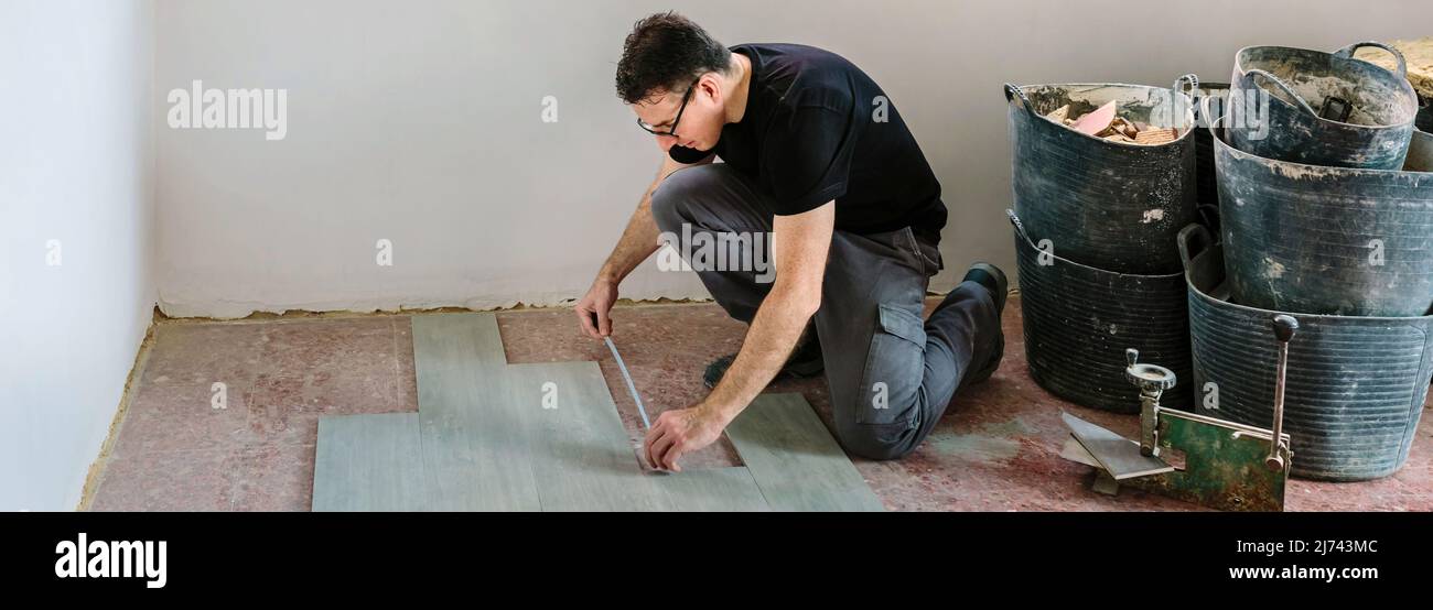 Bricklayer measuring tiles to install a floor Stock Photo Alamy