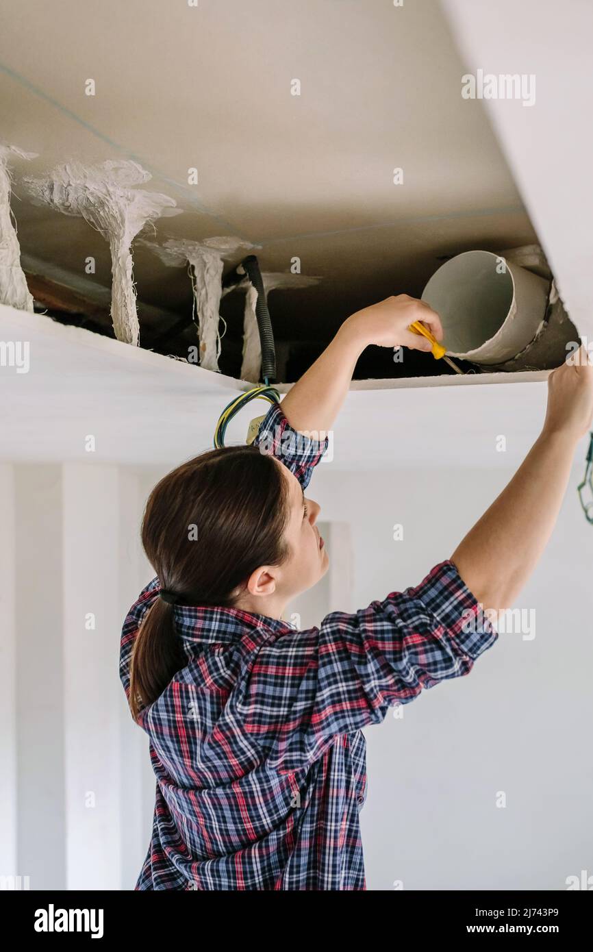 Woman placing tube for kitchen hood installation Stock Photo