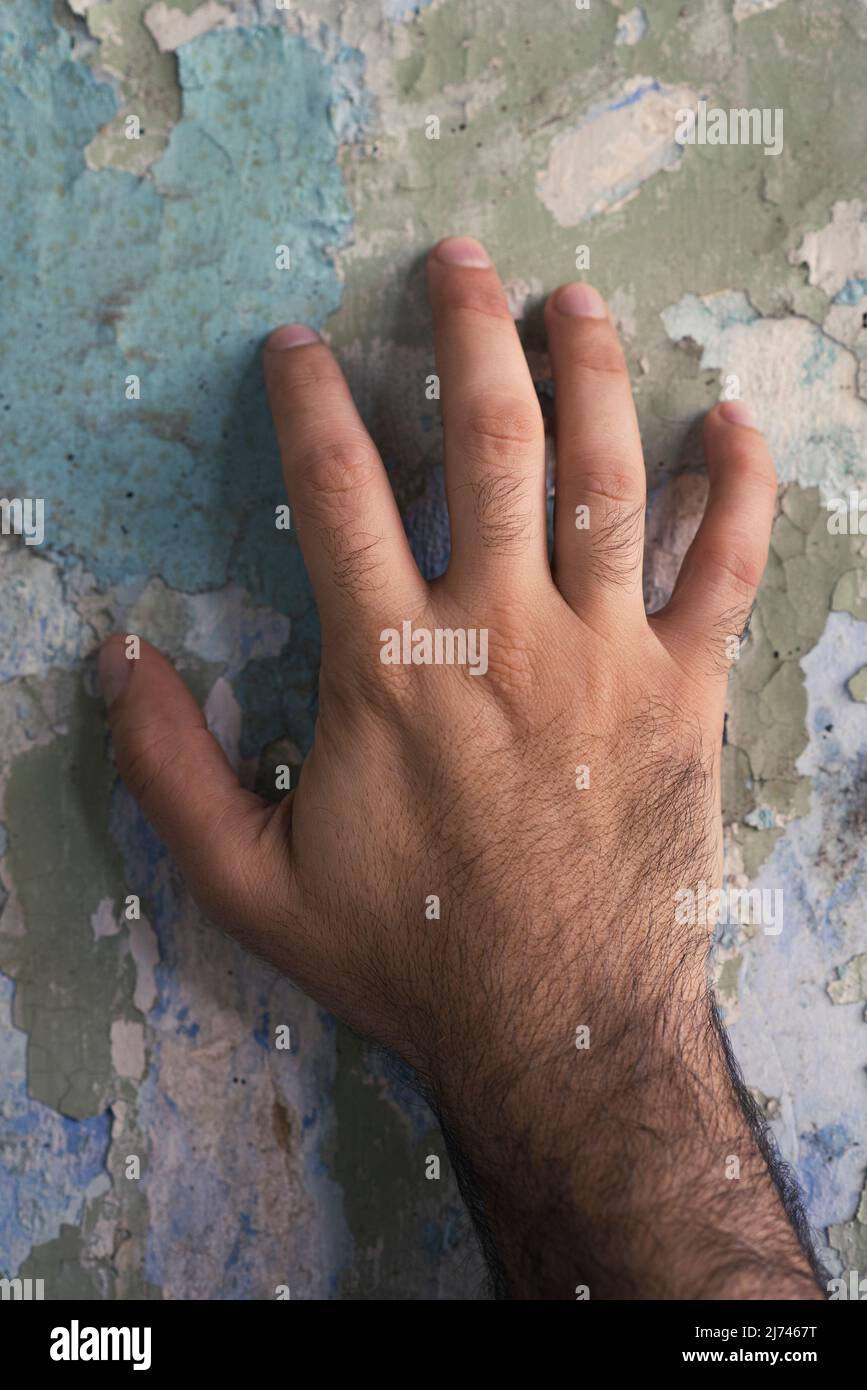 Close up of man's hand touching peeled wall paint Stock Photo
