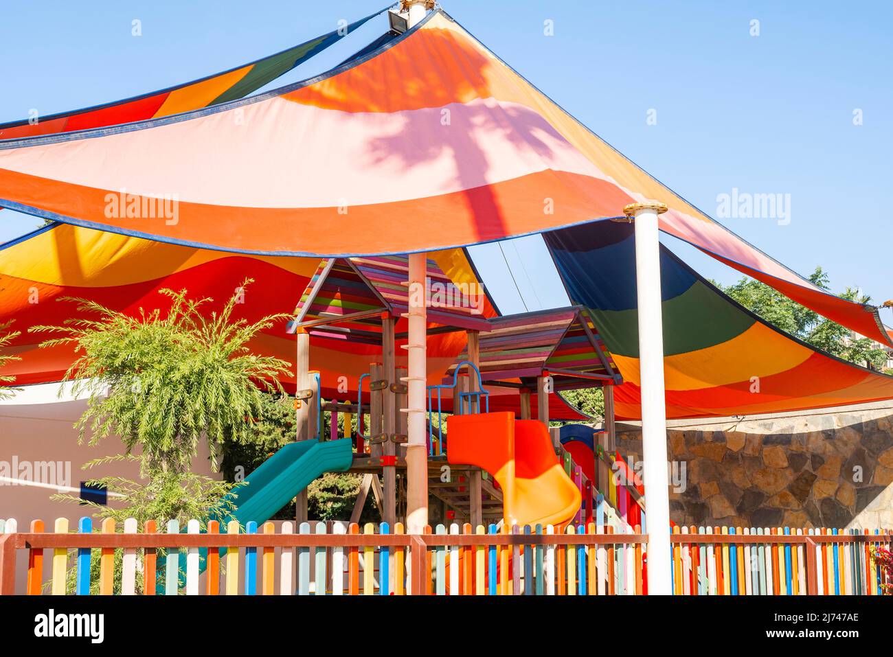 Bright slide and a swing laid on a rubber floor under a canopy. Along